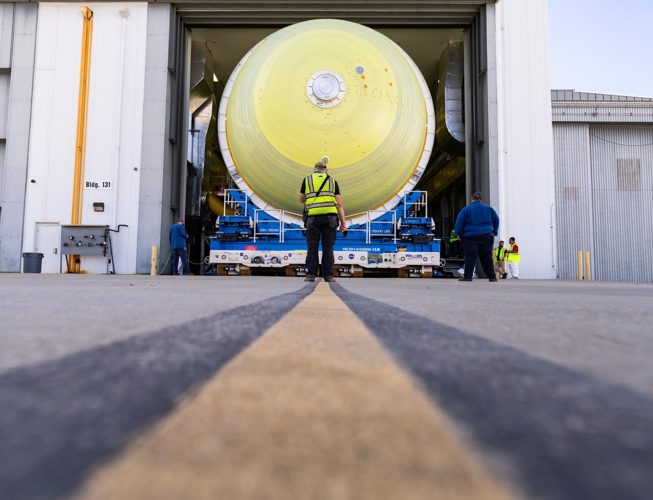 Teams move a liquid hydrogen tank for NASA’s SLS (Space Launch System) rocket out of a priming cell and into an adjacent cell on May 20 at the agency’s Michoud Assembly Facility in New Orleans. Inside the cell, the tank, which will be used on the core stage of NASA’s Artemis III mission, will receive its thermal protection system.  The thermal protection system, or spray-on foam insulation, provides protection to the core stage during launch. It is flexible enough to move with the rocket yet can withstand the aerodynamic pressures as the SLS accelerates from 0 to 17,500 mph and soars to more than 100 miles above the Earth. This third-generation insulation is more environmentally friendly and keeps the cryogenic propellant, which powers the rocket’s four RS-25 engines, extremely cold (the liquid hydrogen must remain at minus 423 degrees Fahrenheit/253 degrees Celsius) to remain in its liquid state. When applied the thermal protection system is a light-yellow color, which “tans” once exposed to the Sun’s ultraviolet rays, giving the SLS core stage its signature orange color.